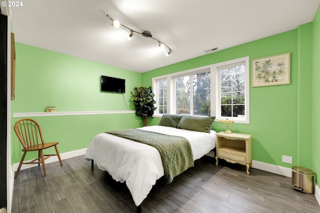 bedroom with hardwood / wood-style flooring, rail lighting, and a textured ceiling