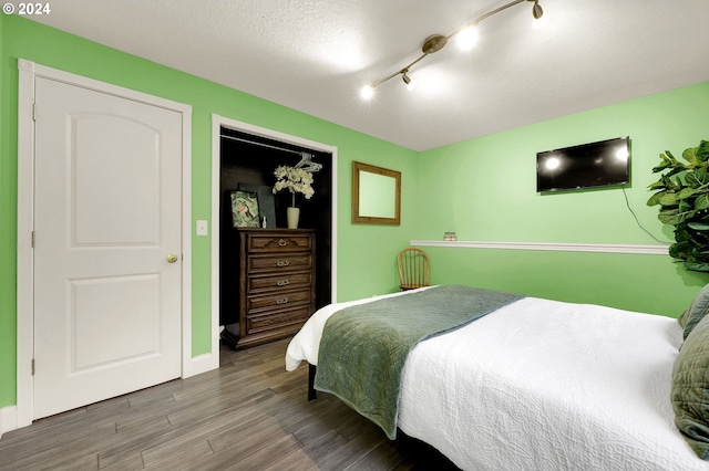 bedroom with hardwood / wood-style floors, a textured ceiling, and rail lighting