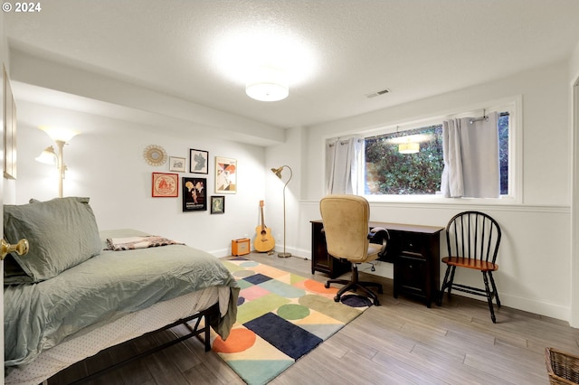 bedroom with a textured ceiling and light hardwood / wood-style flooring