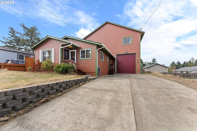 view of front of home with a garage, concrete driveway, and fence