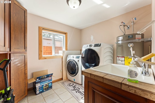 laundry area with light tile patterned floors, baseboards, secured water heater, cabinet space, and washer and clothes dryer