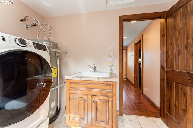 washroom with light hardwood / wood-style floors, cabinets, water heater, sink, and washer / dryer