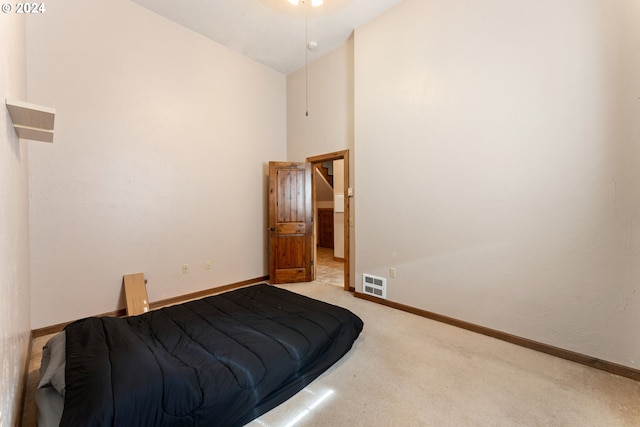 carpeted bedroom with a high ceiling, visible vents, and baseboards