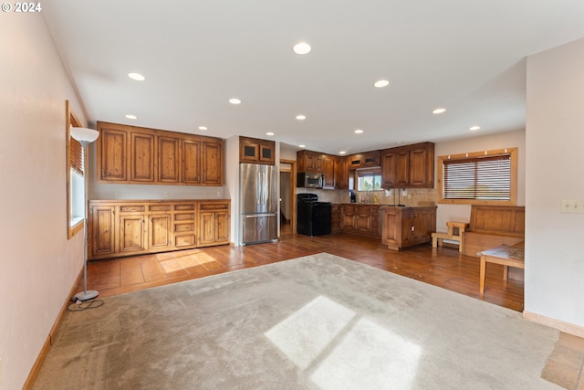 kitchen featuring baseboards, stainless steel appliances, brown cabinets, and recessed lighting