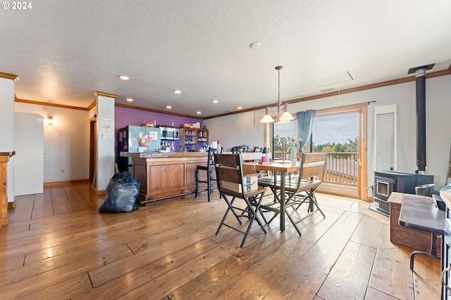 dining space featuring a textured ceiling, recessed lighting, ornamental molding, light wood-type flooring, and a wood stove