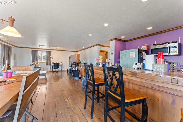 interior space featuring stainless steel microwave, a dry bar, a textured ceiling, and hardwood / wood-style floors