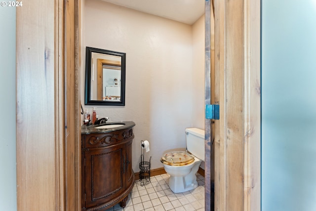 bathroom with toilet, tile patterned flooring, baseboards, and vanity