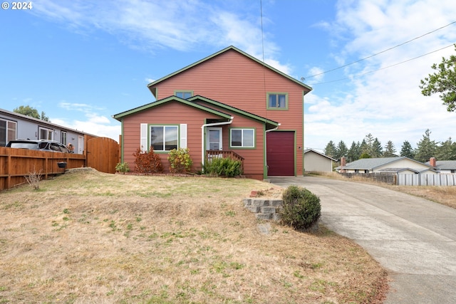 view of front of home with concrete driveway, a front yard, and fence