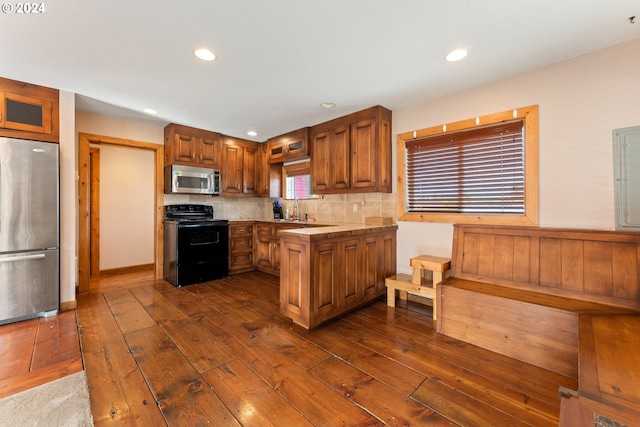 kitchen featuring stainless steel appliances, brown cabinetry, dark wood finished floors, and a sink