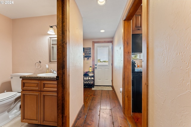 corridor featuring a textured wall, wood-type flooring, a sink, and recessed lighting