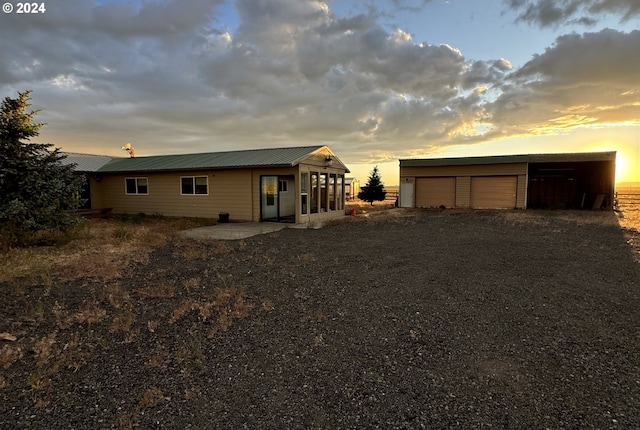 back house at dusk featuring an outdoor structure and a garage