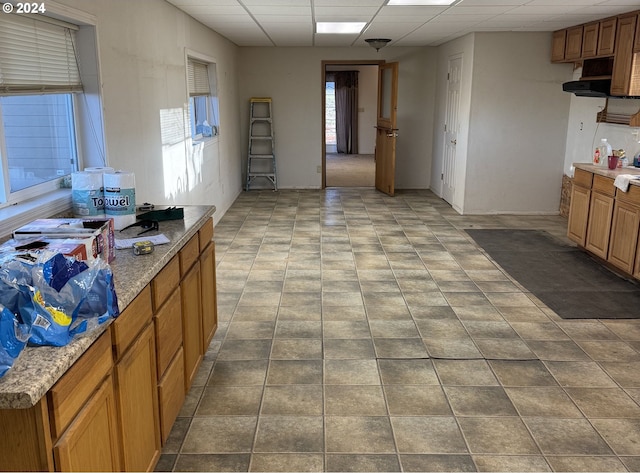 kitchen with light stone countertops and a drop ceiling