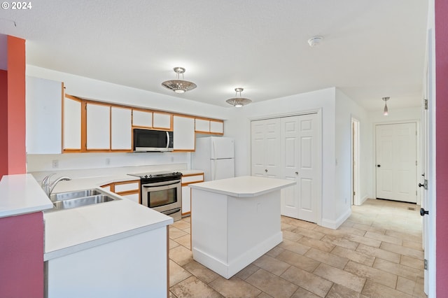 kitchen with a center island, sink, a textured ceiling, appliances with stainless steel finishes, and white cabinetry