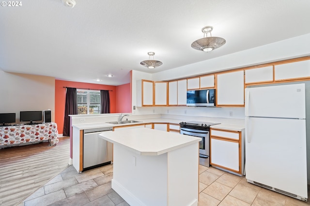 kitchen featuring kitchen peninsula, stainless steel appliances, sink, white cabinets, and a kitchen island