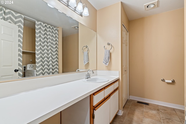 bathroom featuring tile patterned floors, vanity, and washer / dryer