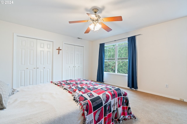 carpeted bedroom with ceiling fan and two closets