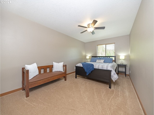 bedroom featuring ceiling fan, light colored carpet, and a textured ceiling