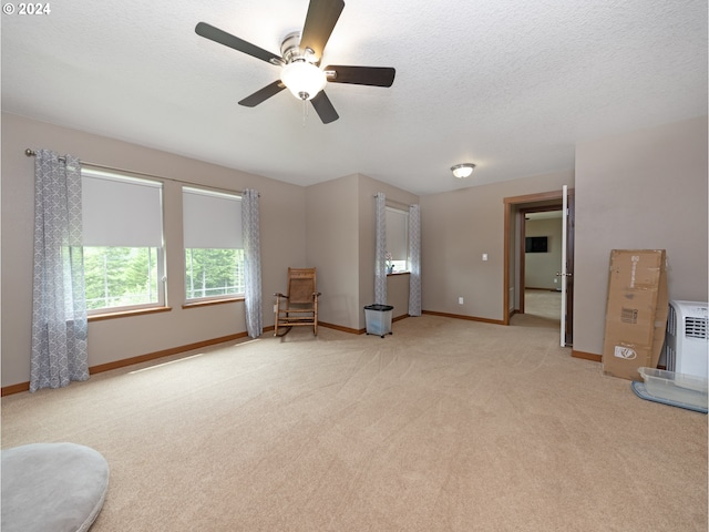 living room featuring ceiling fan, light colored carpet, and a textured ceiling