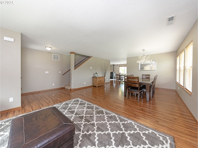 living room with hardwood / wood-style flooring, a textured ceiling, and an inviting chandelier