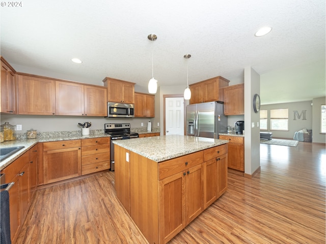 kitchen featuring hanging light fixtures, light hardwood / wood-style flooring, stainless steel appliances, and a center island