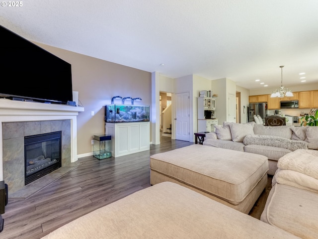 living room with a tile fireplace, dark hardwood / wood-style flooring, and a notable chandelier