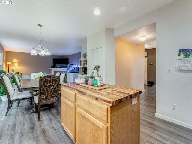 kitchen featuring pendant lighting, a kitchen island, butcher block counters, light hardwood / wood-style floors, and a notable chandelier