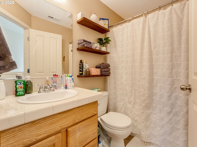 bathroom featuring a textured ceiling, toilet, and vanity