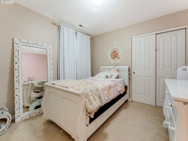 carpeted bedroom with a textured ceiling and a closet