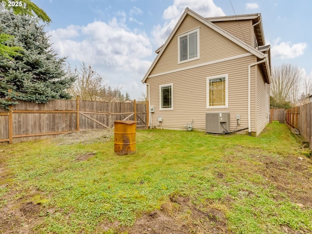 rear view of property featuring a yard and central air condition unit