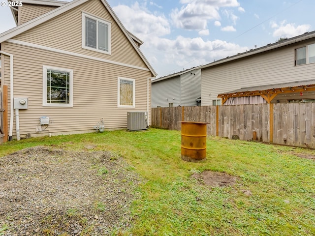 back of property with central AC and a lawn