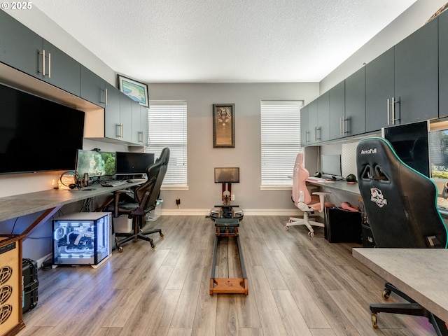 office area with built in desk, a textured ceiling, and light hardwood / wood-style floors