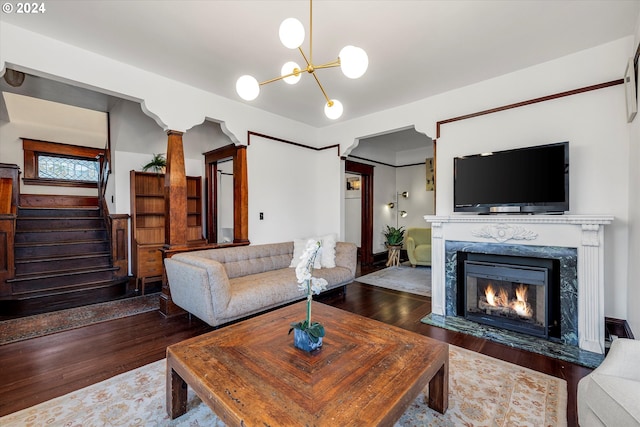 living room with a high end fireplace, dark wood-type flooring, and a notable chandelier