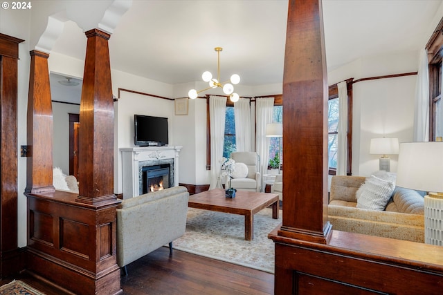 living room with dark hardwood / wood-style floors, decorative columns, a notable chandelier, and a premium fireplace