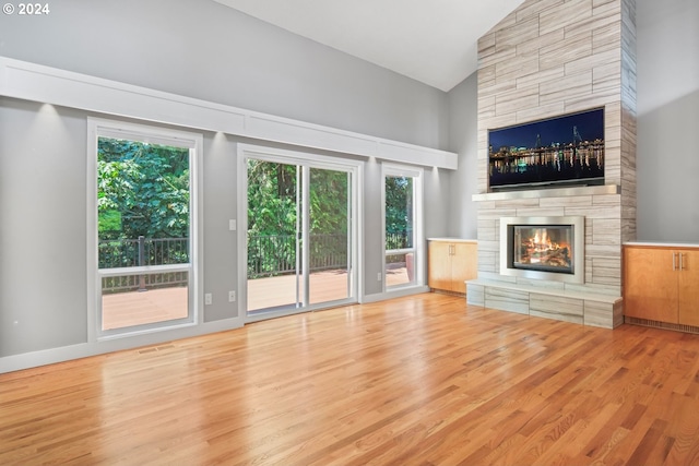 unfurnished living room featuring a fireplace, visible vents, wood finished floors, high vaulted ceiling, and baseboards