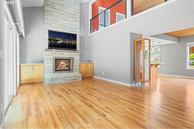 unfurnished living room with baseboards, wood finished floors, and a stone fireplace