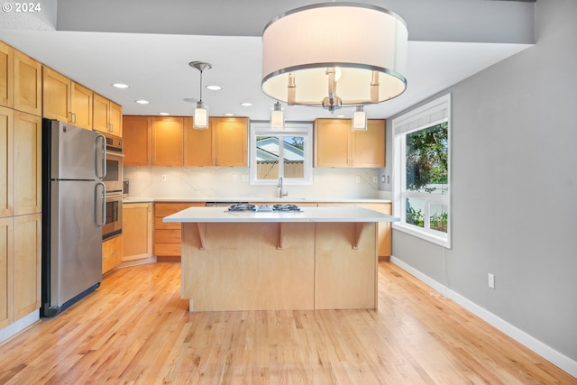 kitchen with a kitchen bar, a kitchen island, stainless steel appliances, and light countertops