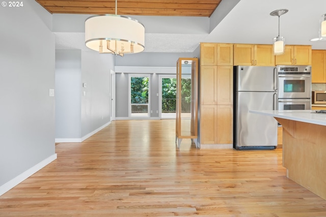 kitchen featuring light brown cabinetry, light countertops, appliances with stainless steel finishes, and decorative light fixtures