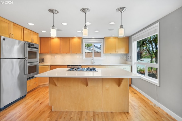 kitchen with light countertops, appliances with stainless steel finishes, a kitchen island, and pendant lighting