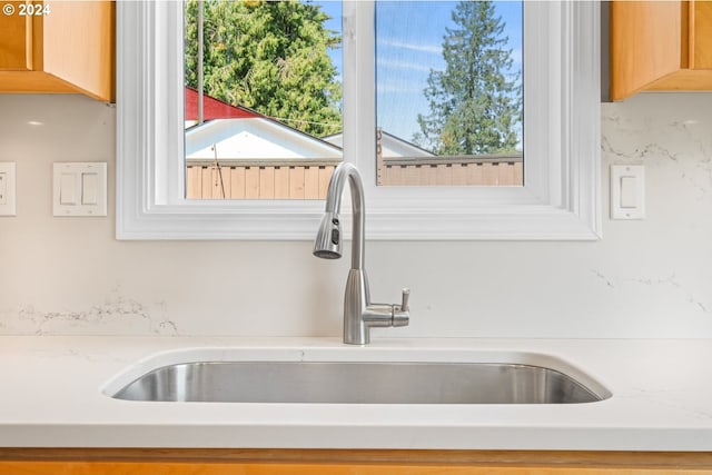 interior details featuring light stone countertops, a sink, and light brown cabinetry