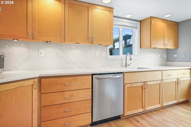 kitchen with a sink, light countertops, dishwasher, light wood finished floors, and tasteful backsplash