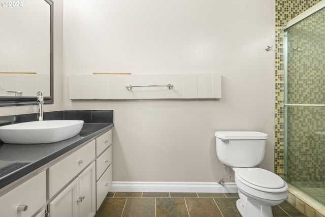 full bathroom featuring toilet, a stall shower, baseboards, and vanity