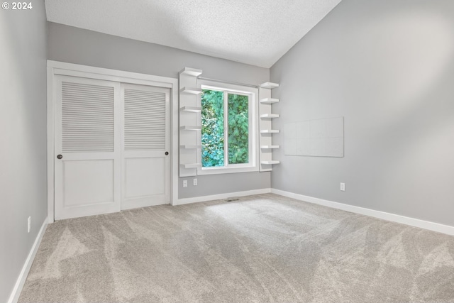 unfurnished bedroom featuring light carpet, a textured ceiling, a closet, and baseboards