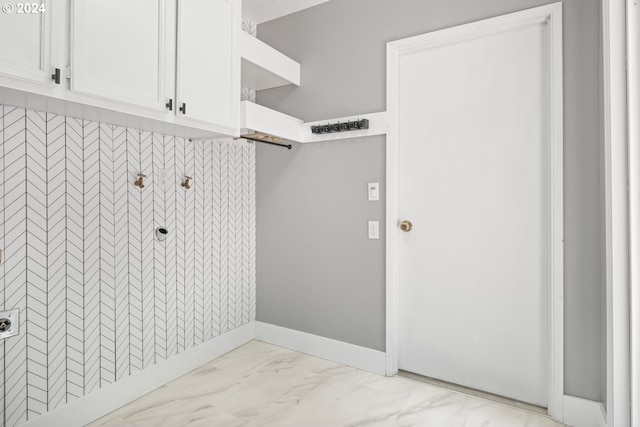 clothes washing area featuring marble finish floor, hookup for an electric dryer, cabinet space, and baseboards