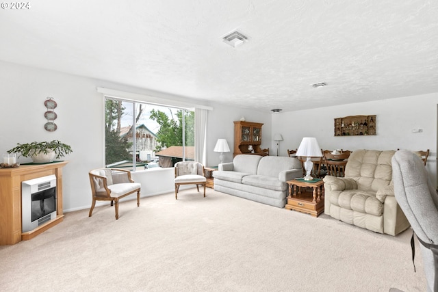 living area featuring visible vents, light colored carpet, heating unit, a glass covered fireplace, and a textured ceiling