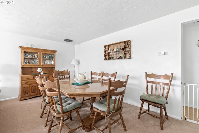 dining space featuring a textured ceiling, baseboards, and light carpet