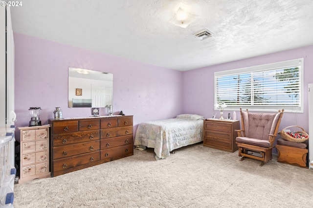 bedroom with visible vents, carpet flooring, and a textured ceiling