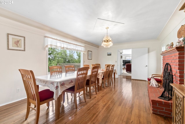 dining space featuring crown molding, dark wood-type flooring, a brick fireplace, and a notable chandelier