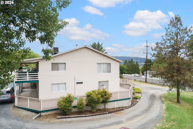 view of side of home featuring a deck with mountain view and driveway