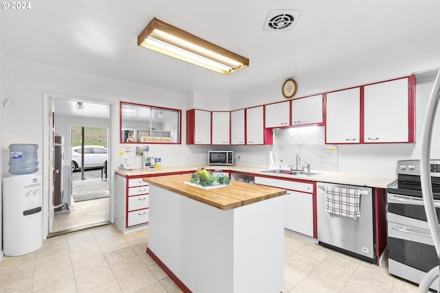 kitchen featuring visible vents, a sink, backsplash, stainless steel appliances, and butcher block counters