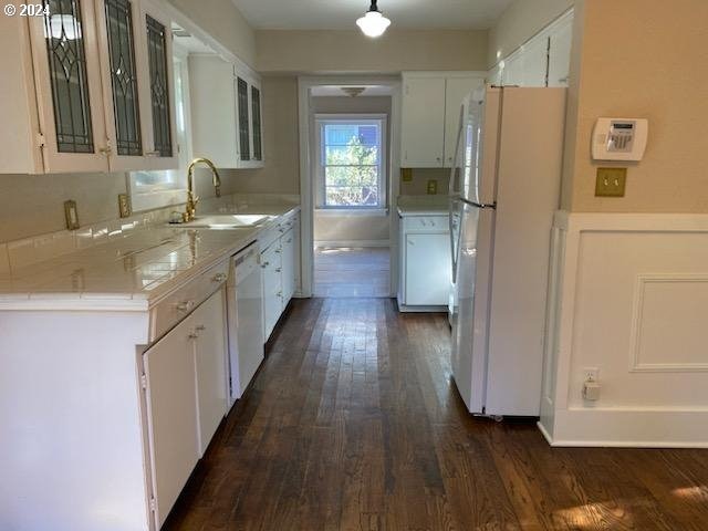 kitchen featuring white cabinets, dark hardwood / wood-style flooring, white appliances, and sink